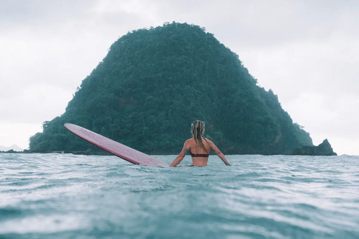 Surfers in the water in front of Red Island, Java