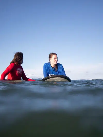 Surf instructor and student sitting on their boards in the water at Spot X