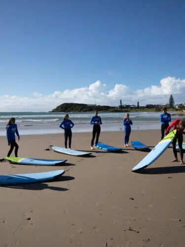Surf lesson group lined up with softboards on the beach