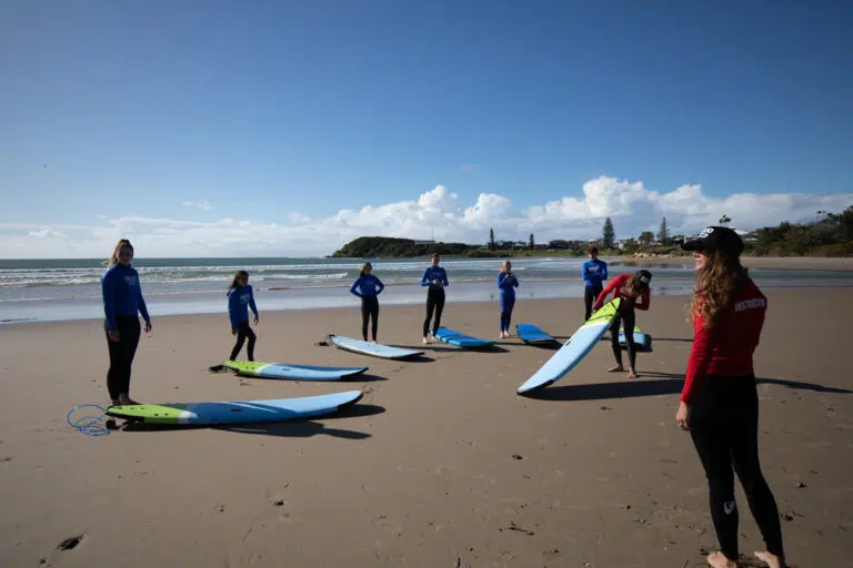 Surf lesson group lined up with softboards on the beach