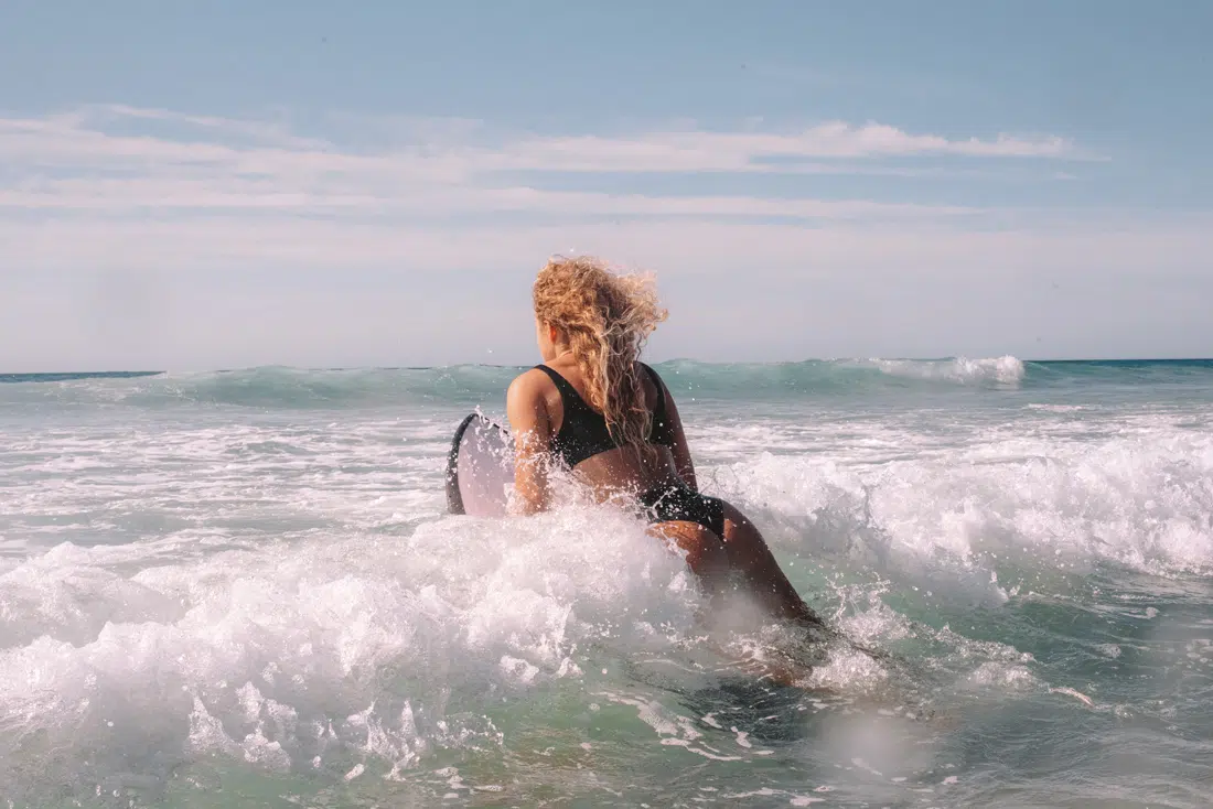 Surfer girl paddling through the whitewash