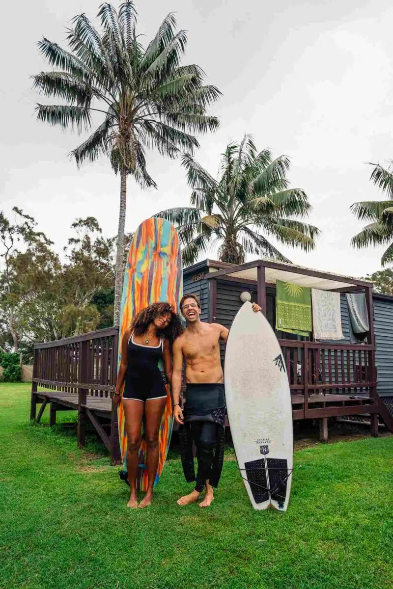 Surf Academy students with boards under palm trees