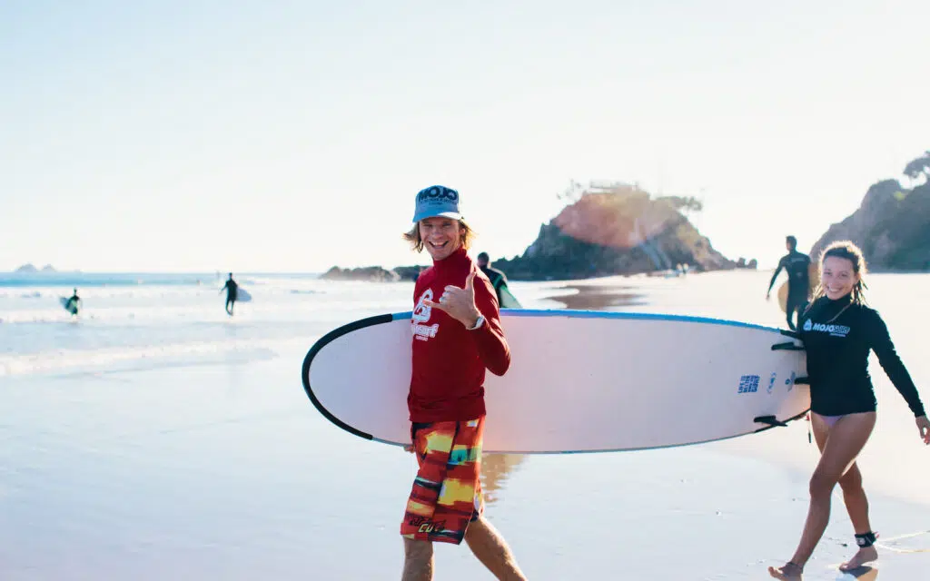 Surf instructors carrying a softboard at Byron Bay