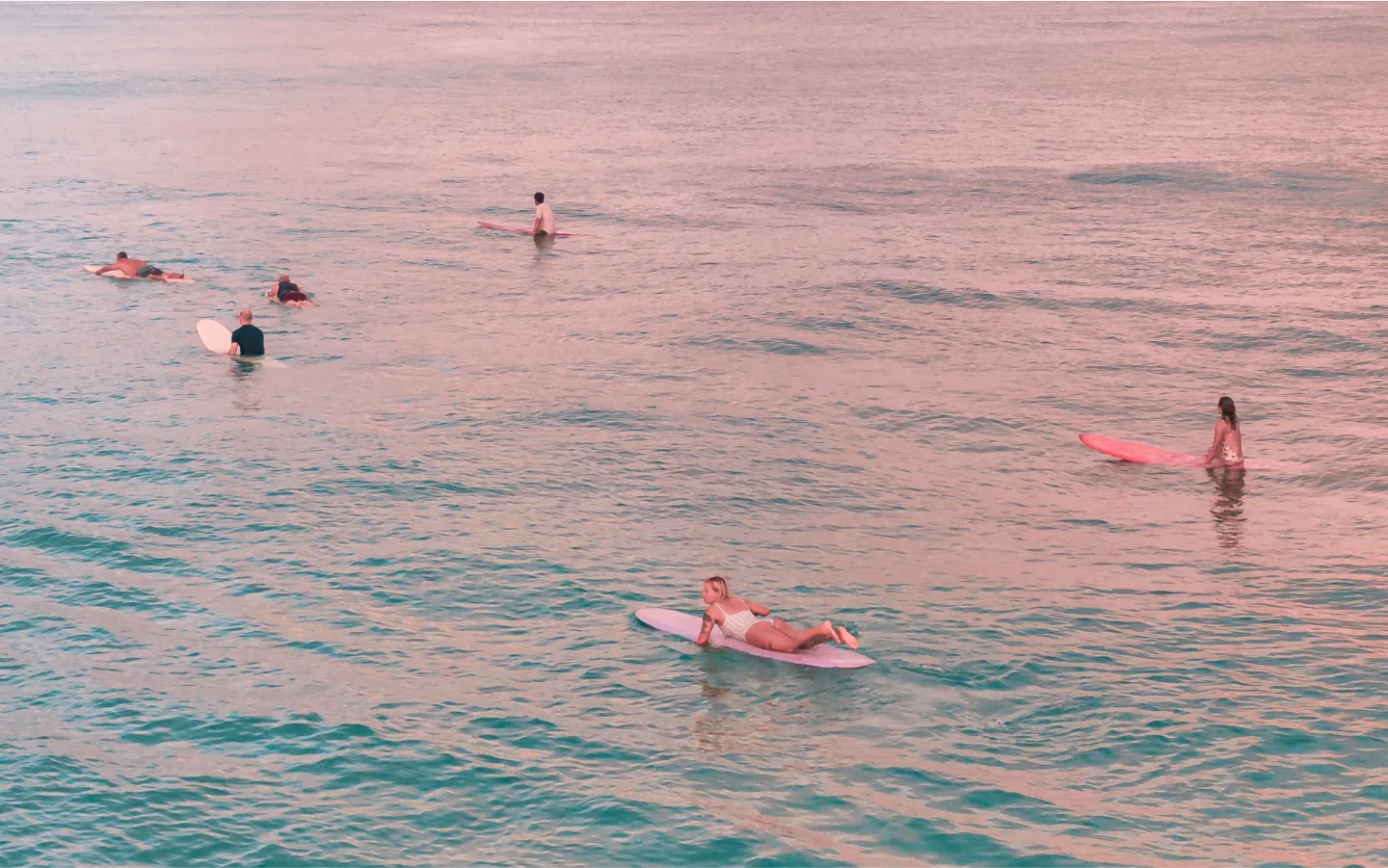 Surfers paddling out at sunrise