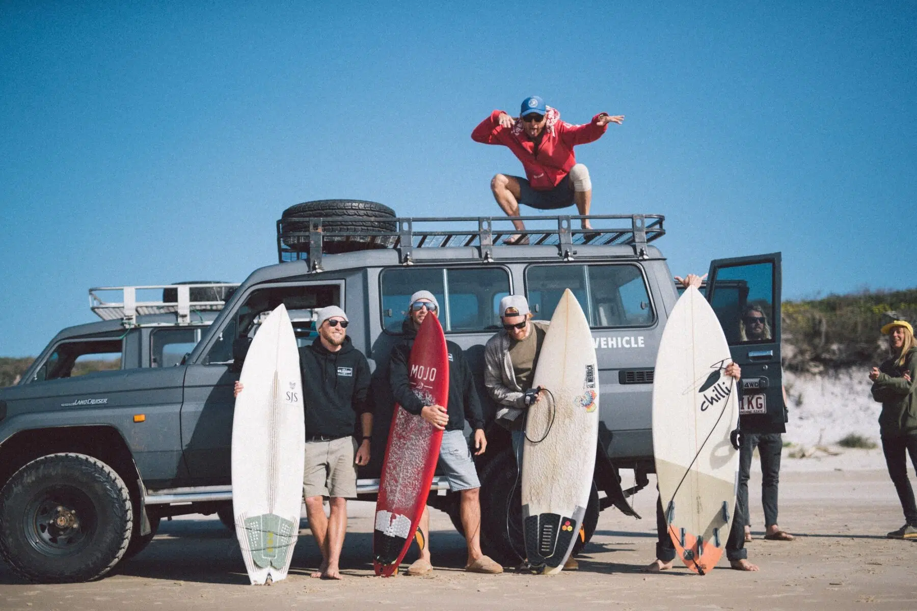 Surf group with boards beside the Mojosurf 4x4 Troopy