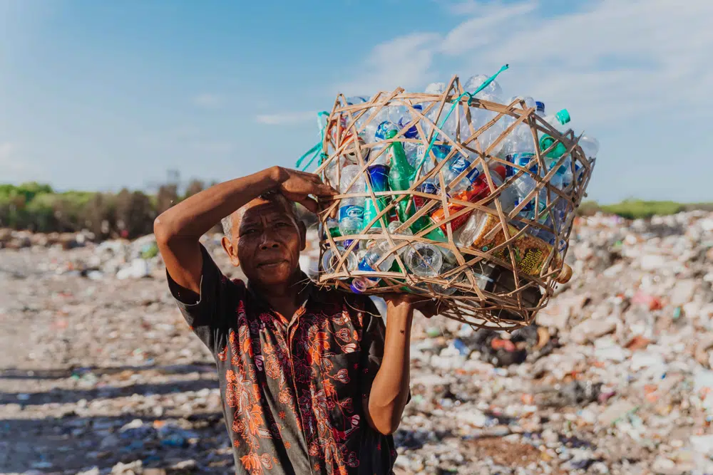 Woman carrying a large bag of collected plastic rubbish