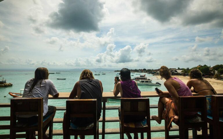 Guests on a balcony looking out over the water at Nusa Lembongan