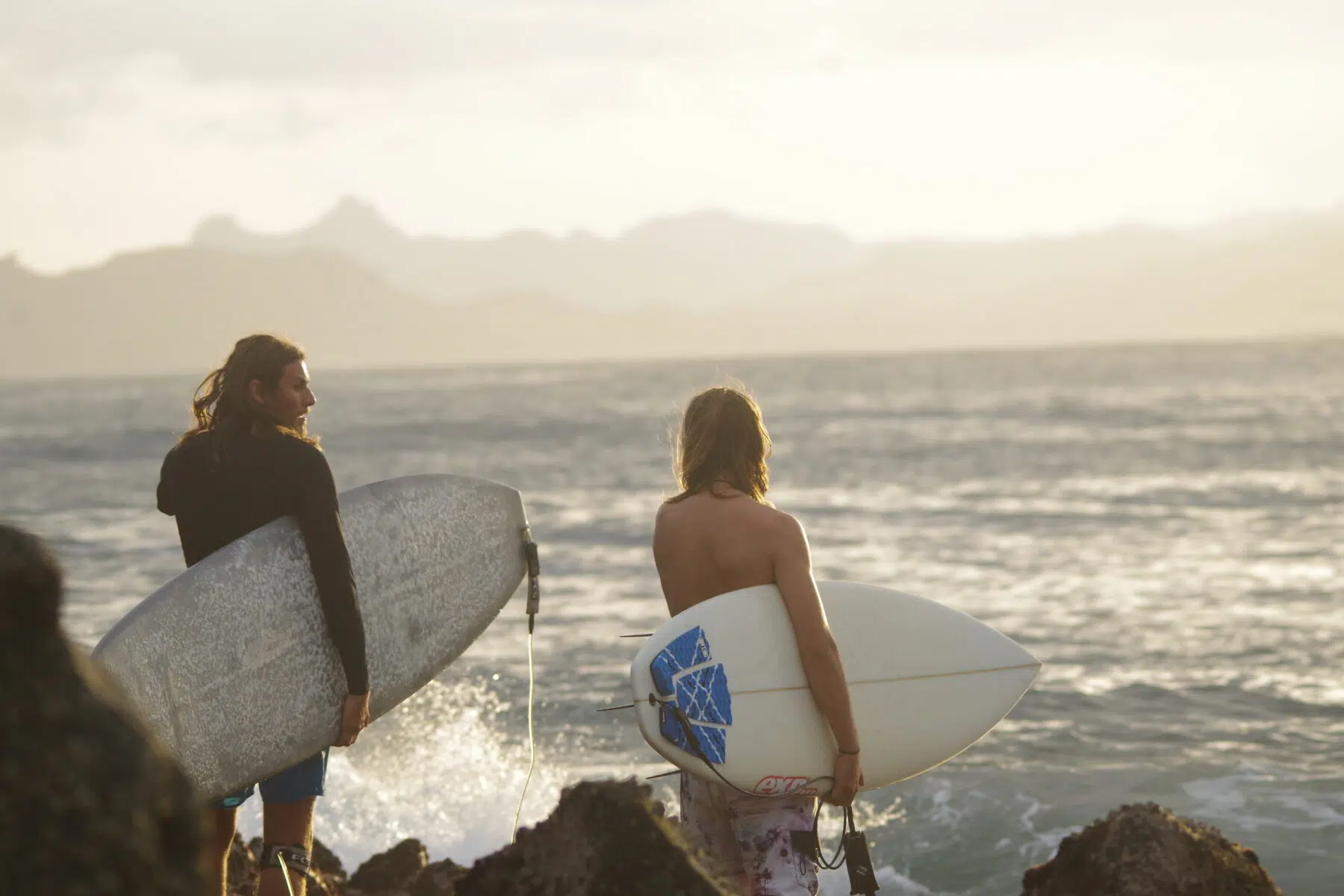 Two surfers heading out into the waves with their boards