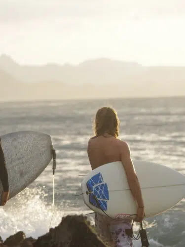 Two surfers heading out into the waves with their boards