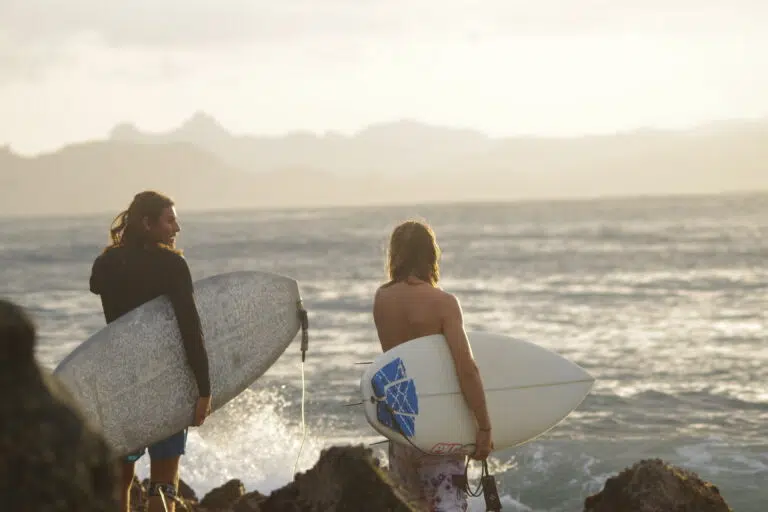 Two surfers heading out into the waves with their boards