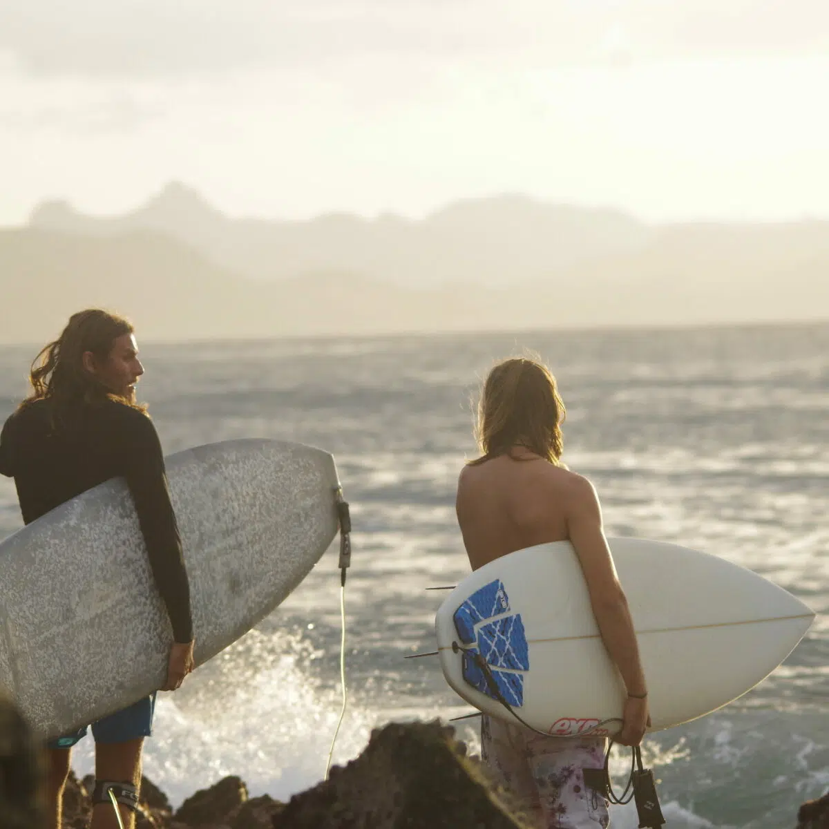Two surfers heading out into the waves with their boards