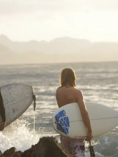 Two surfers heading out into the waves with their boards