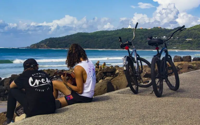 Friends resting on the beach next to their bikes in Byron Bay