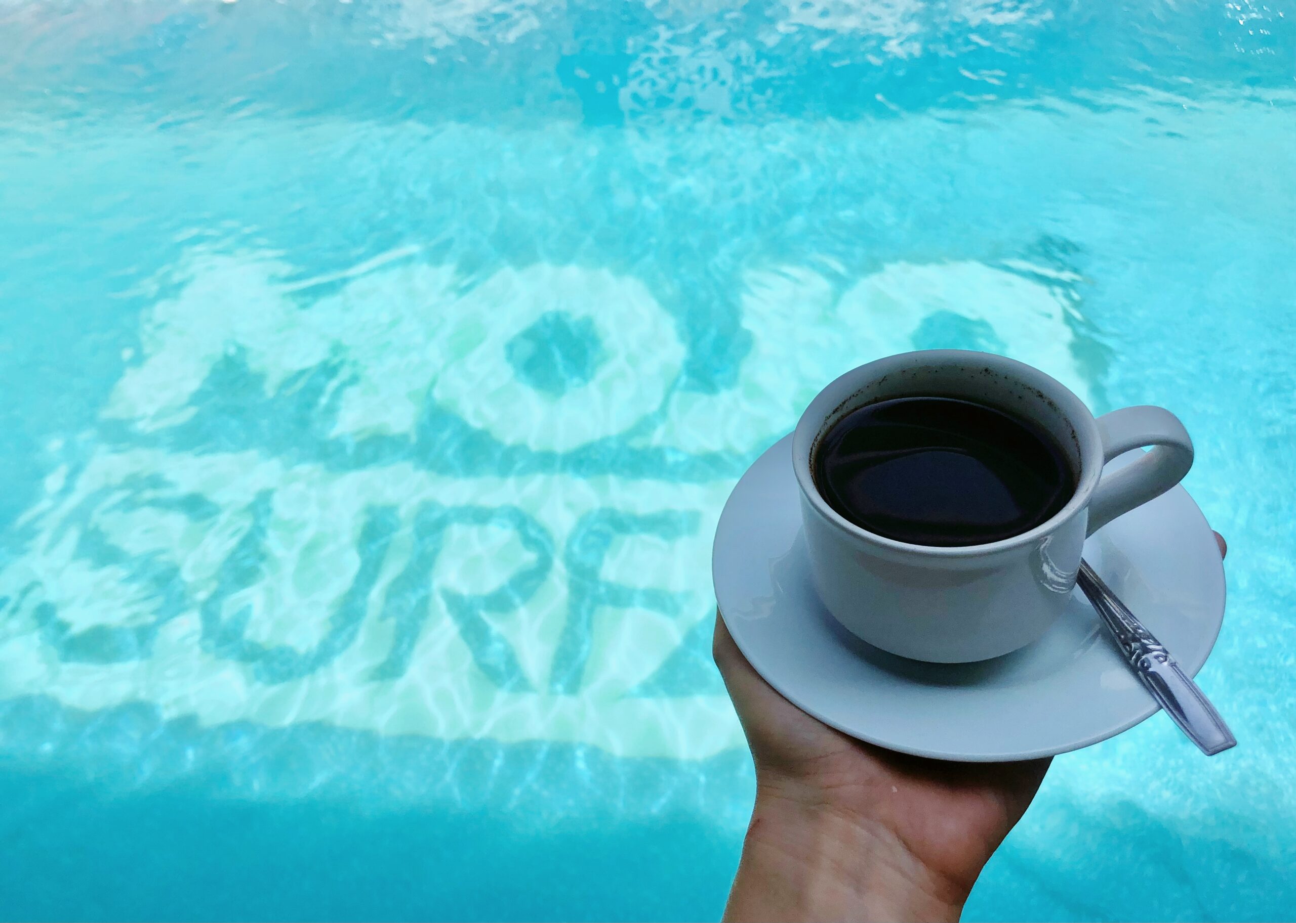 Cup of Bali Coffee with Mojo Surf pool on the background