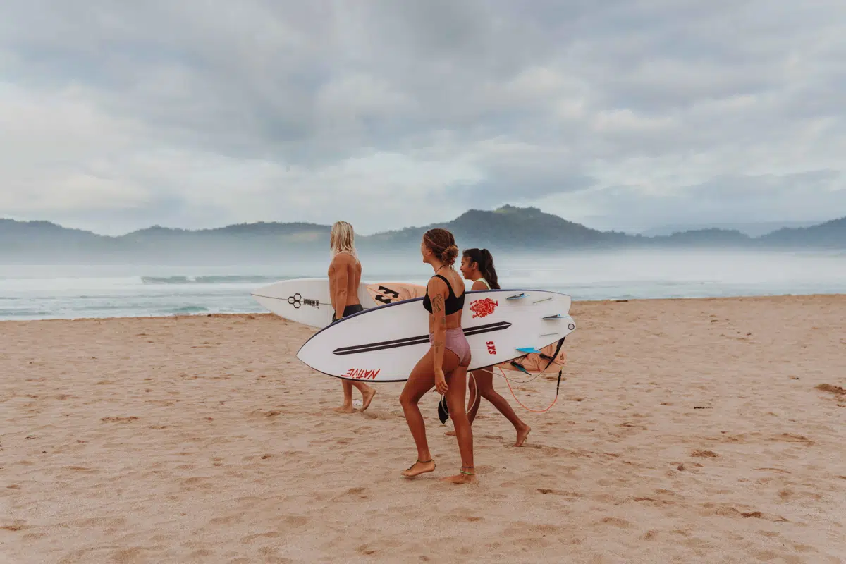 Group of surfers carrying boards along the beach