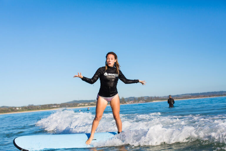 Learner surfer standing up on a softboard at Byron Bay