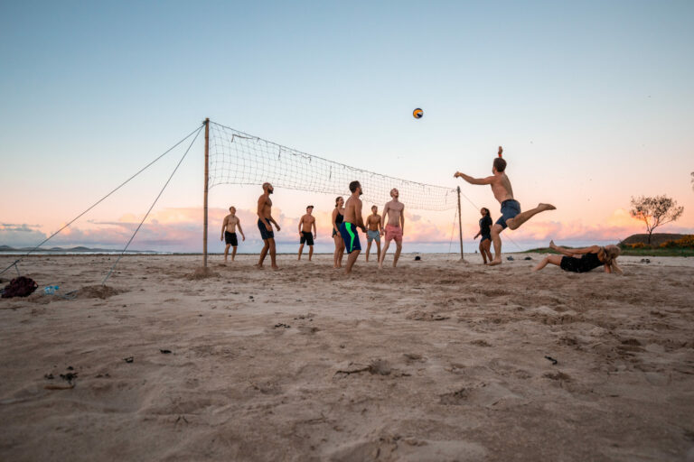 Guests playing beach volleyball at sunset