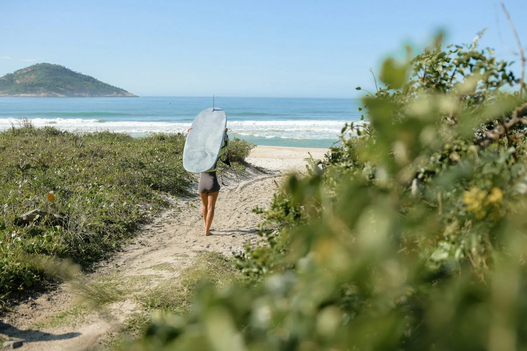 Surfer walking along a coastal track to the beach in Australia