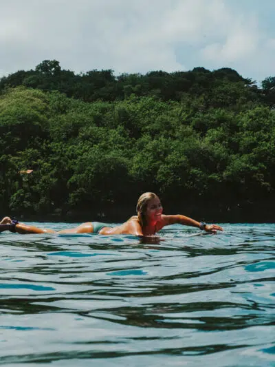 Surfer paddling near a green headland at Nusa Lembongan