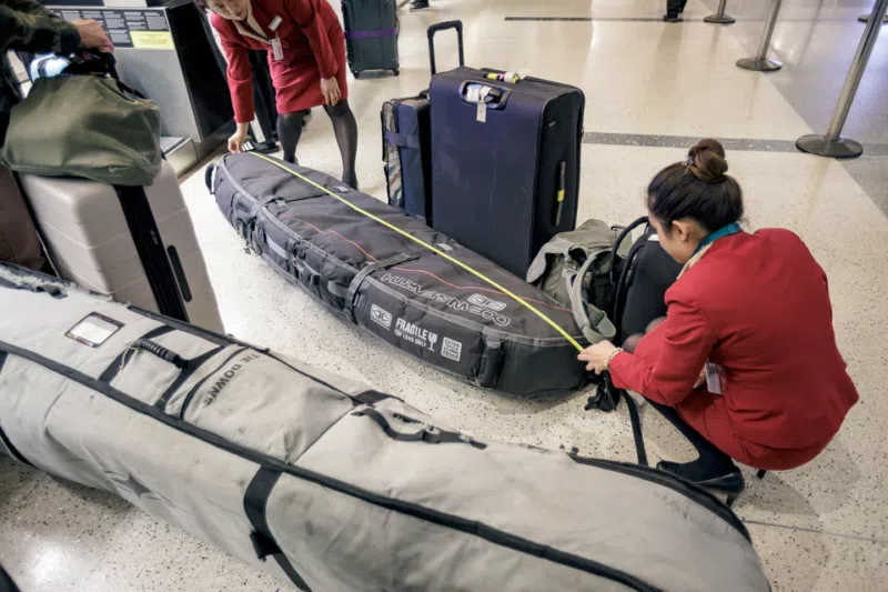Airline staff measuring a surfboard bag at check-in