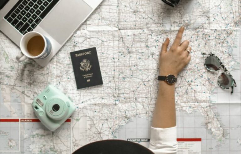 Travel planning flat lay with a map, passport, camera and coffee