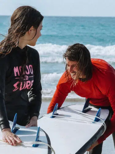 Surf instructor coaching a student in a wetsuit