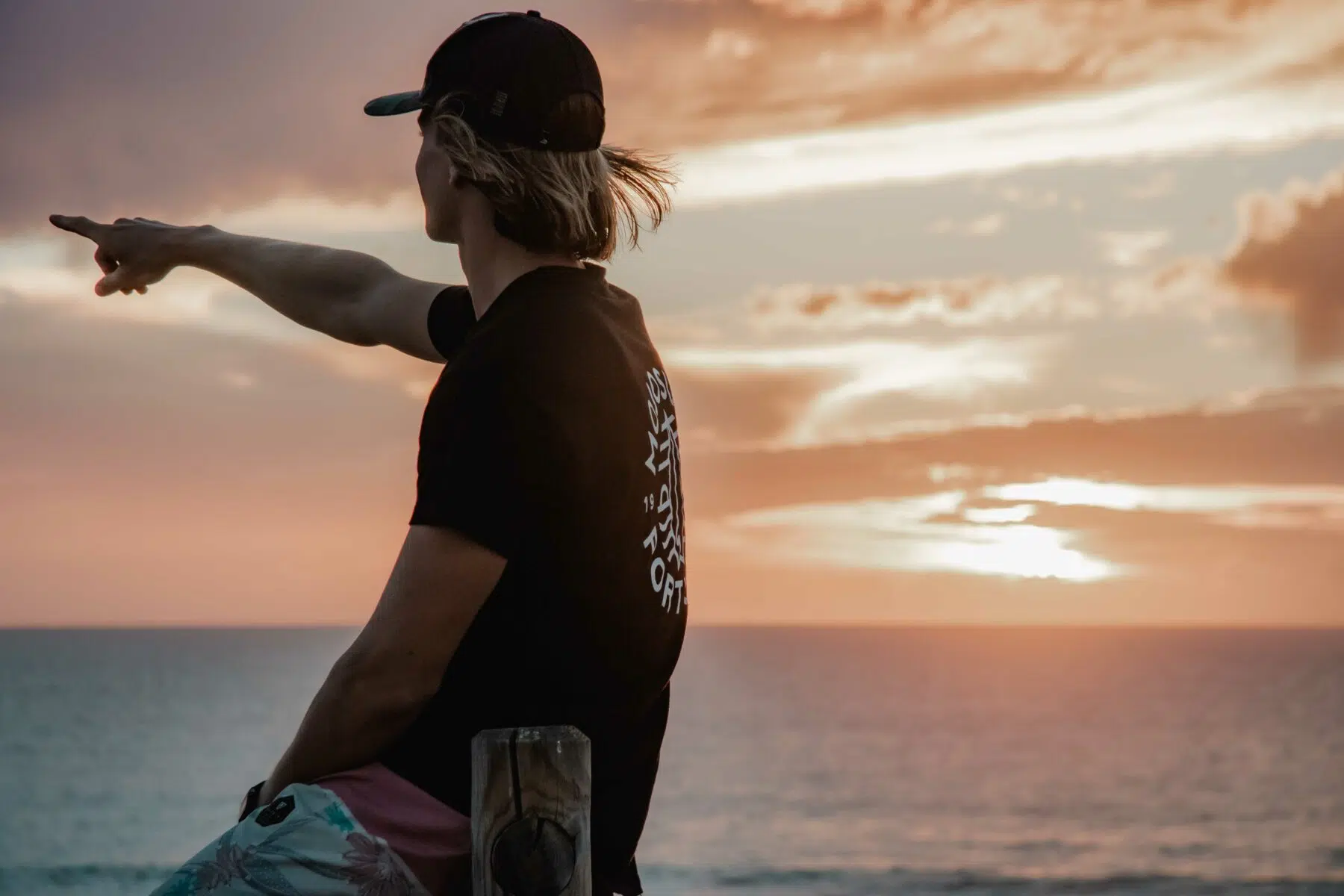 Surfer pointing out to sea at sunset in Peniche