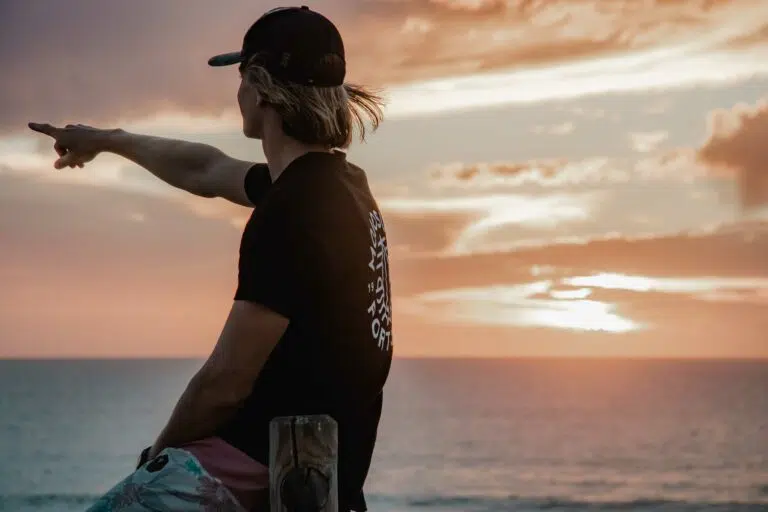 Surfer pointing out to sea at sunset in Peniche